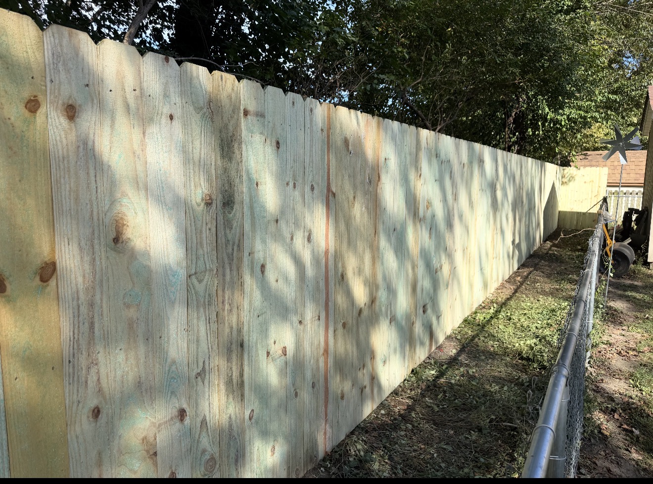 Long wood privacy fence beside an existing chain link fence