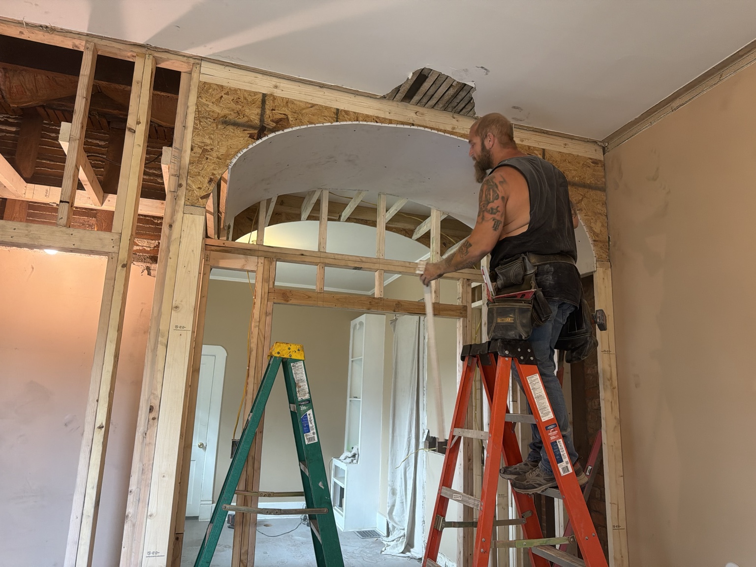 Carpenter on a ladder fitting material around an interior archway