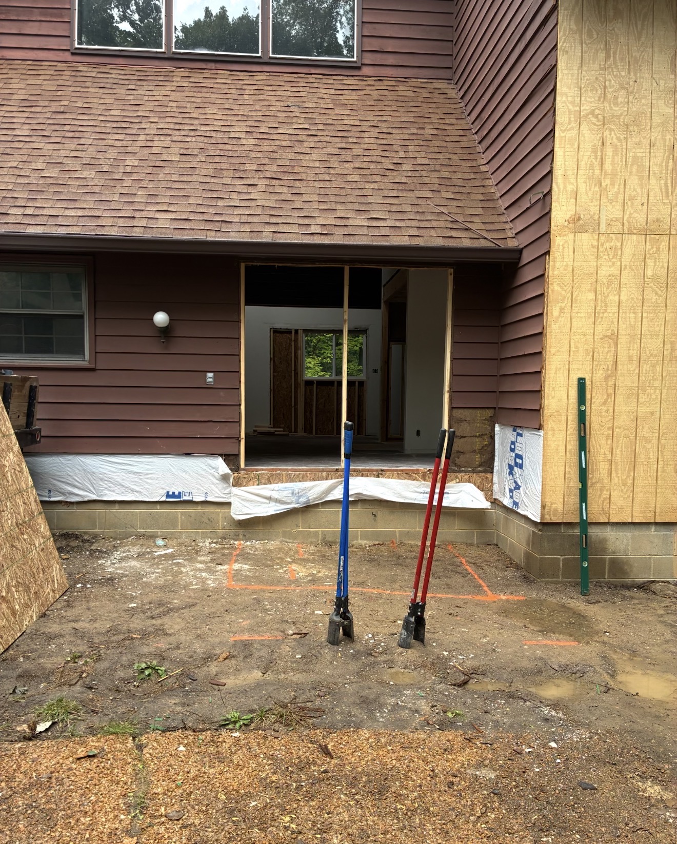 House entry with marked dirt footings and tools before porch construction